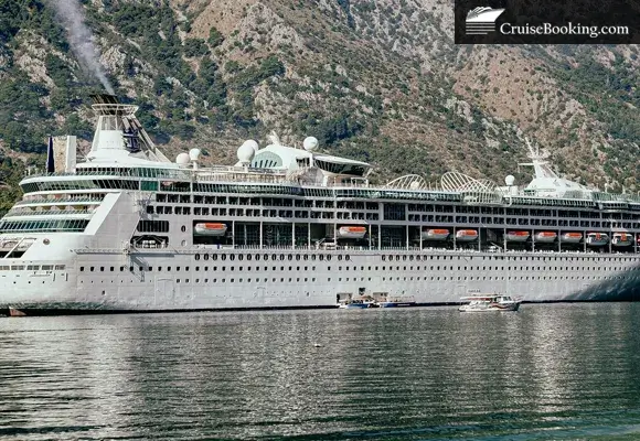 Large cruise ship docked, mountains in background