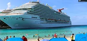 Carnival Breeze cruise ship docked on the beach, with people swimming and relaxing under umbrellas.