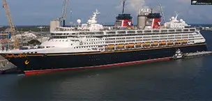 Disney Wonder cruise ship docked at a port with cranes in the background