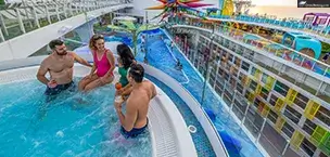 On Icon of the Seas, two couples are in a hot tub overlooking the pool; friends enjoy cocktails.