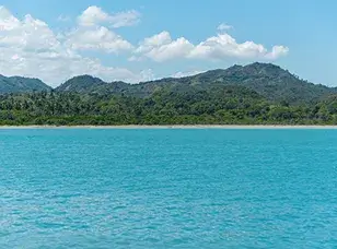 A large cruise ship docked at Amber Cove in the Dominican Republic. The ship is surrounded by clear blue water, with lush green hills in the background.