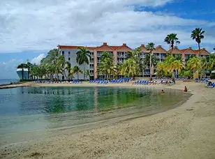 A photo of the Renaissance Wind Creek Aruba Resort, showcasing a modern and luxurious beachfront property with multiple pools, palm trees, and a white sandy beach.