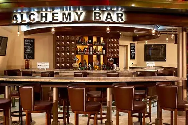 A bar sign with the words ALCHEMY BAR in large letters and the letters RSWEDUP below in a smaller font, with an arrow pointing to the left.