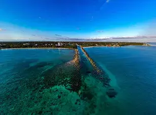 Aerial view of Xanadu Beach in Freeport, Grand Bahama. The image showcases a pristine stretch of white sandy beach, turquoise water, and lush greenery.