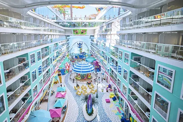 An aerial view of the Surfside neighborhood onboard Icon of the Seas. Drone shot, merry-go-round, shops, aqua colors,