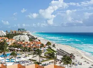 Aerial view of Cancun, Mexico, showcasing its white sandy beaches, turquoise Caribbean waters, and a sprawling coastline lined with luxury resorts.