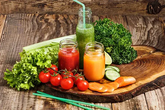 Fresh vegetable juice bottles on a wooden table