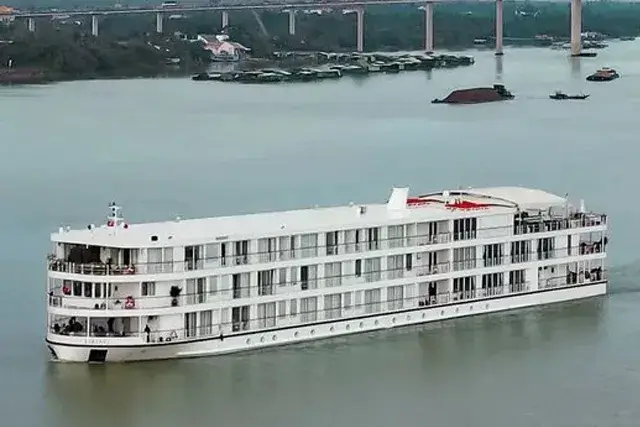 White Viking Tonle cruise ship sailing down a river. In the background are small buildings