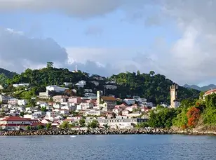 Aerial view of Grenada, showcasing its lush green interior, pristine white sandy beaches, and crystal-clear turquoise waters.