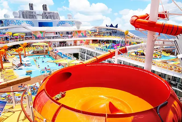 The Wonder of the Seas, a man lying on Perfect Storm slide, wide view of the pool deck in the background.